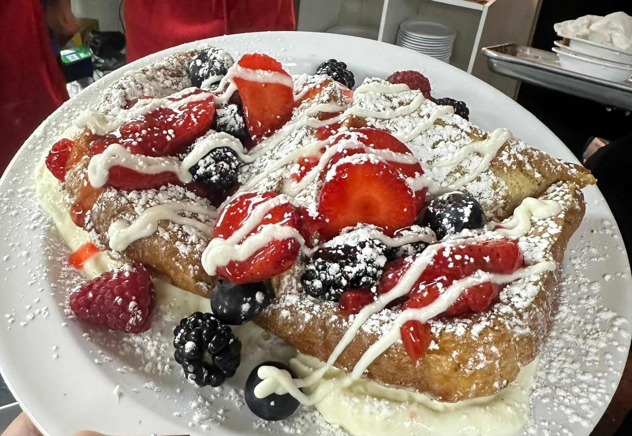 Powdered sugar-dusted fried pastry topped with fresh berries